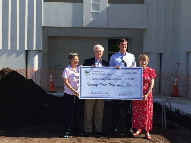 4 people holding a large sized check for the Beaches Library for $25,000